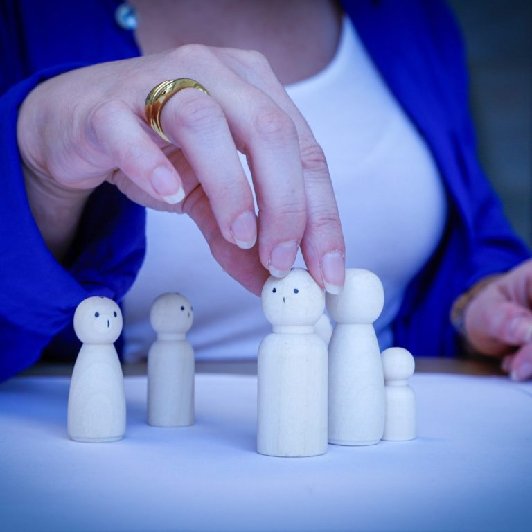 Nahaufnahme von einer Hand bei der Arbeit mit Figuren – Anwendung von Familienaufstellung in der systemischen Beratung.